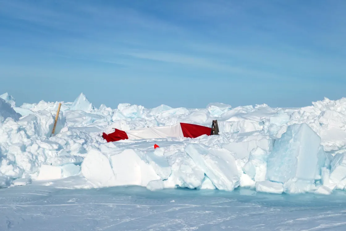 A tent compresses under the pressure of Arctic sea ice ridging, showing increased instability in the region surrounding the RV Polarstern. Surface melt appears at the forefront of the image.